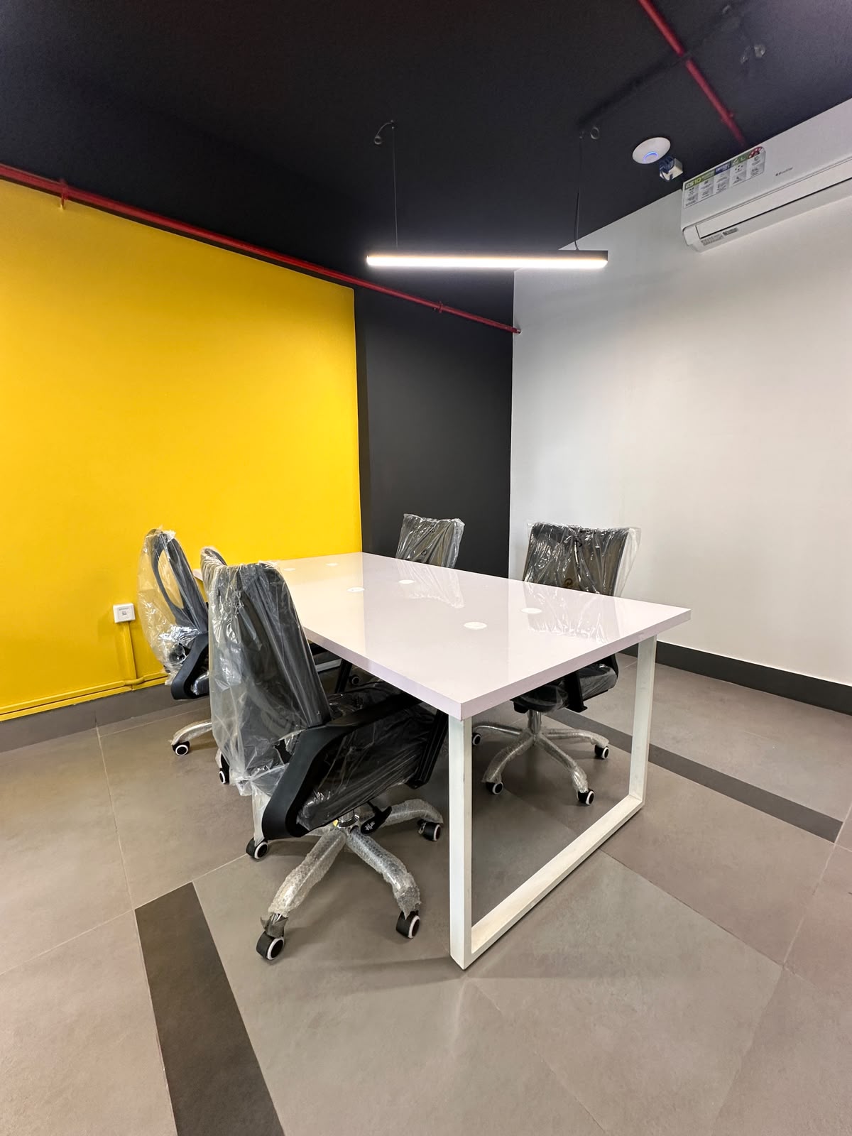 Meeting room with yellow accent wall at WorkMore, The Pavilion
