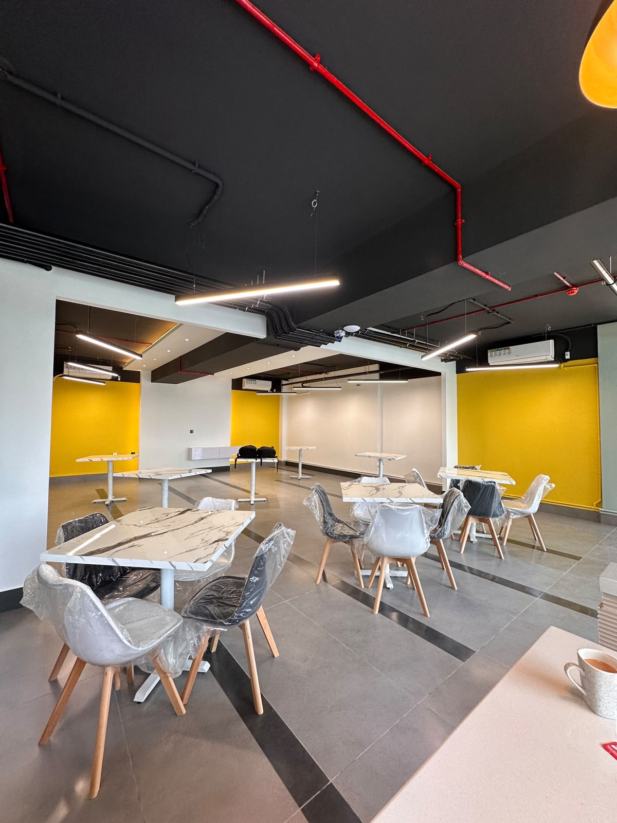 Open community and event area with yellow accent walls at WorkMore, The Pavilion