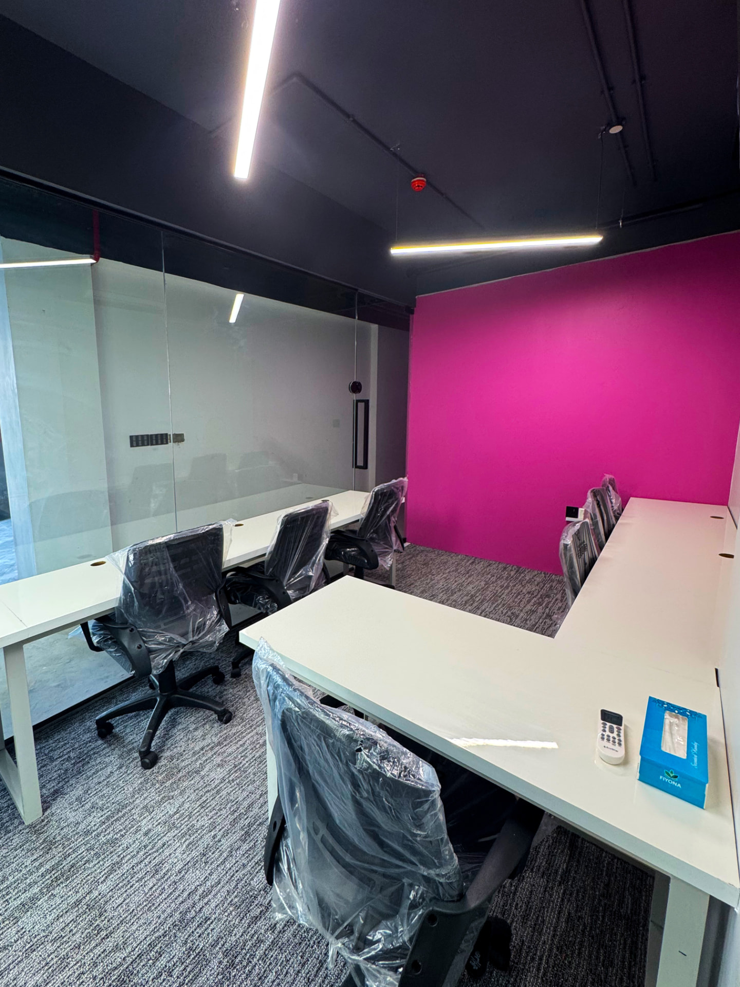 Team room with pink accent wall and glass partitions at WorkMore, The Pavilion